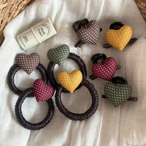 Close-up of cute polka dot heart hair clips and elastic scrunchies in various berry colors