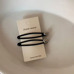 Vue détaillée de deux barrettes à cheveux noires avec des accents de cœur en argent