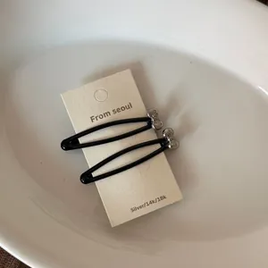 Paire de barrettes à cheveux en métal noir avec petits nœuds argentés sur carte