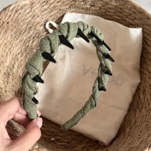 Détail d'un serre-tête à pointes enveloppé de tissu vert dans un panier rustique.