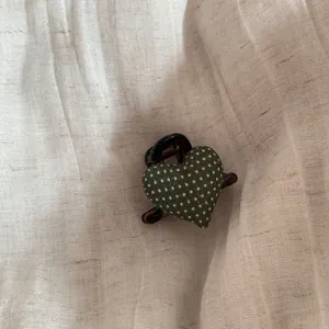 Macro view of a cute green polka dot fabric heart hair claw clip on linen background