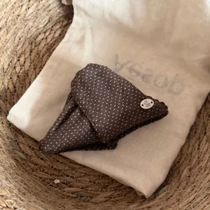 Gros plan d'un accessoire pour cheveux à pois marron avec un joli charm d'ours en argent