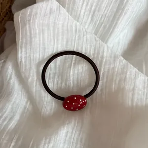 Detalle de un coletero rojo con lunares blancos y colgante ovalado minimalista.