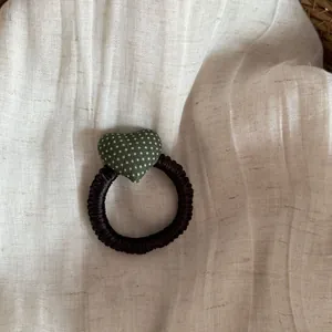 Close-up detail of high-elasticity hair tie with green polka dot heart on linen