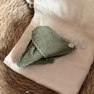 Vue détaillée d'un nœud papillon à pois vert olive avec un bouton décoratif en forme d'ours.