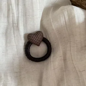Detailed view of a dark brown elastic hair scrunchie with a brown polka dot padded heart charm.