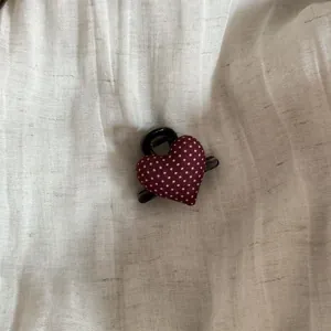 Detailed view of a maroon polka dot heart hair claw clip on textured linen background