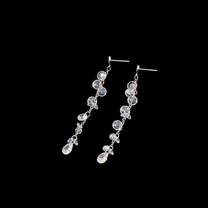 Detail view of elegant zircon tassel earrings with sparkling teardrop crystals on black