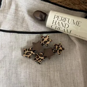 Detail view of leopard print and brown fabric star hair clips on a linen background
