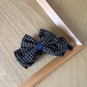 Macro view of vintage brown gingham checkered bow hair clip on a wooden surface