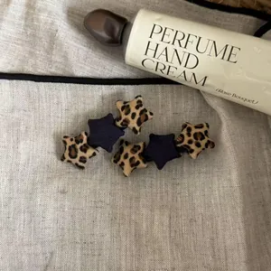 Close-up view of stylish leopard print and navy fabric star hair clips on linen background