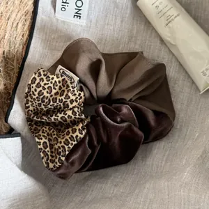 Detail showing patchwork leopard print, brown fabric, and velvet scrunchie texture.