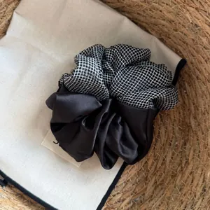 Detailed view of a black satin and grid pattern oversized Korean style hair scrunchie