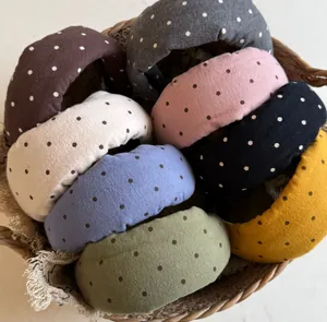 Dettaglio di cerchietti imbottiti a pois vintage in vari colori in un cesto.