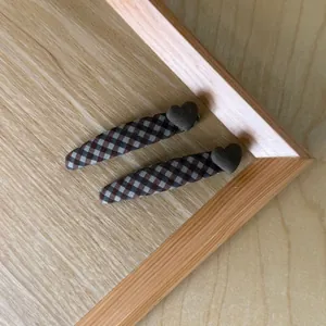Close-up of vintage brown plaid hair clips with heart detail on a wooden surface