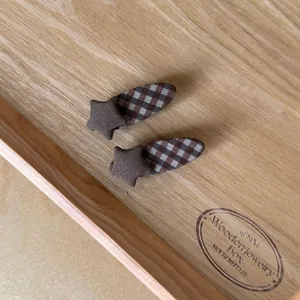 Close-up detail of vintage brown checkered star hair clips displayed on a wooden tray