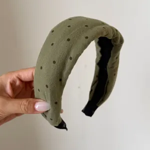 Primo piano di una fascia vintage a pois verdi con un design morbido a tesa larga