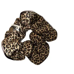 Stylish leopard print scrunchie hair tie featuring a vintage button and brand label
