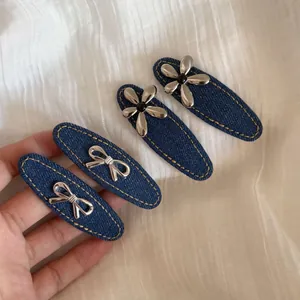 Lot de quatre barrettes en denim bleu avec des breloques argentées en forme de fleur et de nœud