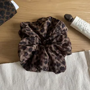 Leopard print scrunchie hair tie with brown tones shown in a lifestyle setting