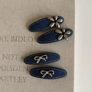 Vue détaillée de barrettes en jean bleu avec des fleurs argentées et des nœuds