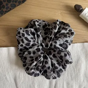 Close-up detail of a large grey and black leopard print scrunchie hair accessory