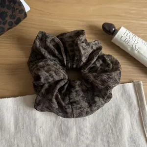 Detailed close-up view of a brown leopard print scrunchie on a warm rustic wooden surface