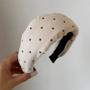 Primo piano di un cerchietto imbottito beige retrò a pois con morbida trama in cotone