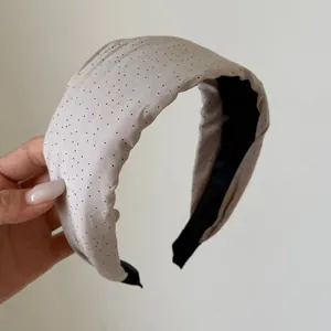 Close-up of a stylish padded cream polka dot headband featuring a black lining.