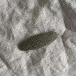 Detailansicht einer grünen Haarklammer mit Punkten auf einem Leinenhintergrund