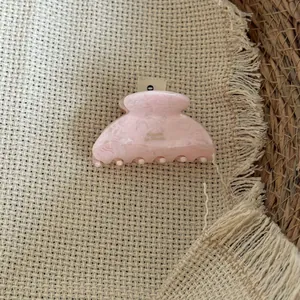 Nahaufnahme einer rosa marmorierten Haarklammer aus Acetat mit feiner Textur.