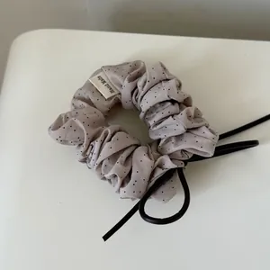 Korean style polka dot scrunchie with ruffled edge and black leather bow detail