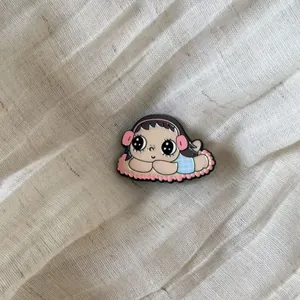 Detailed close-up of a retro cartoon girl enamel pin on textured fabric background