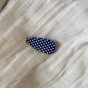 Detailed macro view of a vintage blue teardrop hair clip with white polka dots pattern