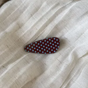 Detailed view of a vintage style acetate hair clip with light blue polka dots on brown.