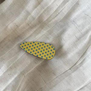 Acetate teardrop hair clip with yellow and blue polka dot pattern on linen background