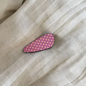 Detailed macro view of a pink acetate hair clip with yellow polka dots on linen fabric
