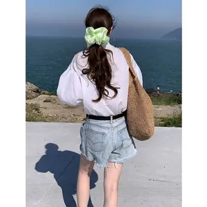 Detailed back view of a woman wearing a pale green satin oversized scrunchie in hair