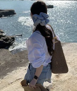 Close-up of oversized light blue satin scrunchie on model at the seaside