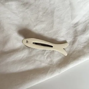 Detalle de cerca de una pinza para el pelo de pececito crema con un ojo de strass