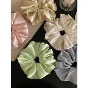 Detailed view of glossy satin scrunchies in pastel colors for elegant hairstyles
