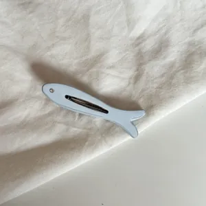 Primer plano de una pinza para el pelo con forma de pez azul y ojo de diamante.