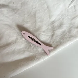 Primer plano de un adorable clip para el cabello con forma de pez rosa y cristal brillante