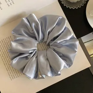 Close-up detail of a silver-blue satin scrunchie showing the glossy silk fabric texture
