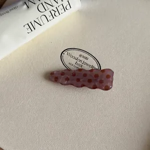 Macrobeeld van een golvende roze-bruine acetaat haarklem met een bruin vintage stippenpatroon