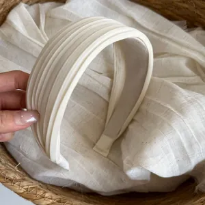Detailansicht der eleganten plissierten Textur und des breiten weißen Satin-Stirnbandes.