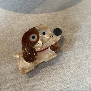 Detailed view of a cute dog-shaped acetate hair claw clip with a marble brown texture.