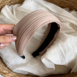 Detailansicht eines hellrosa gefalteten Satin-Stirnbands mit einer feinen Rippenstruktur