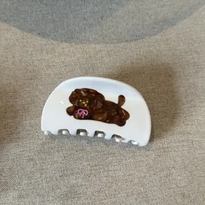 Detail shot of a white acetic acid hair claw clip with a cute brown poodle design.