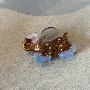 Detail of a brown acetate dog-shaped hair claw clip with a textured fabric backdrop